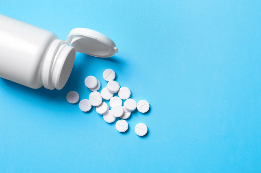 Pills and bottle on light blue background, above view. Space for text nouveau traitement